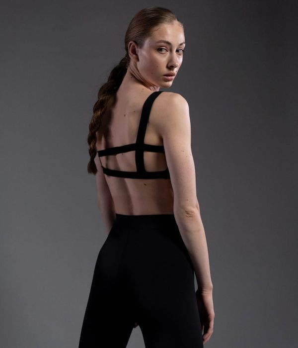Woman in a graceful yoga pose against a dark, minimalist background.
